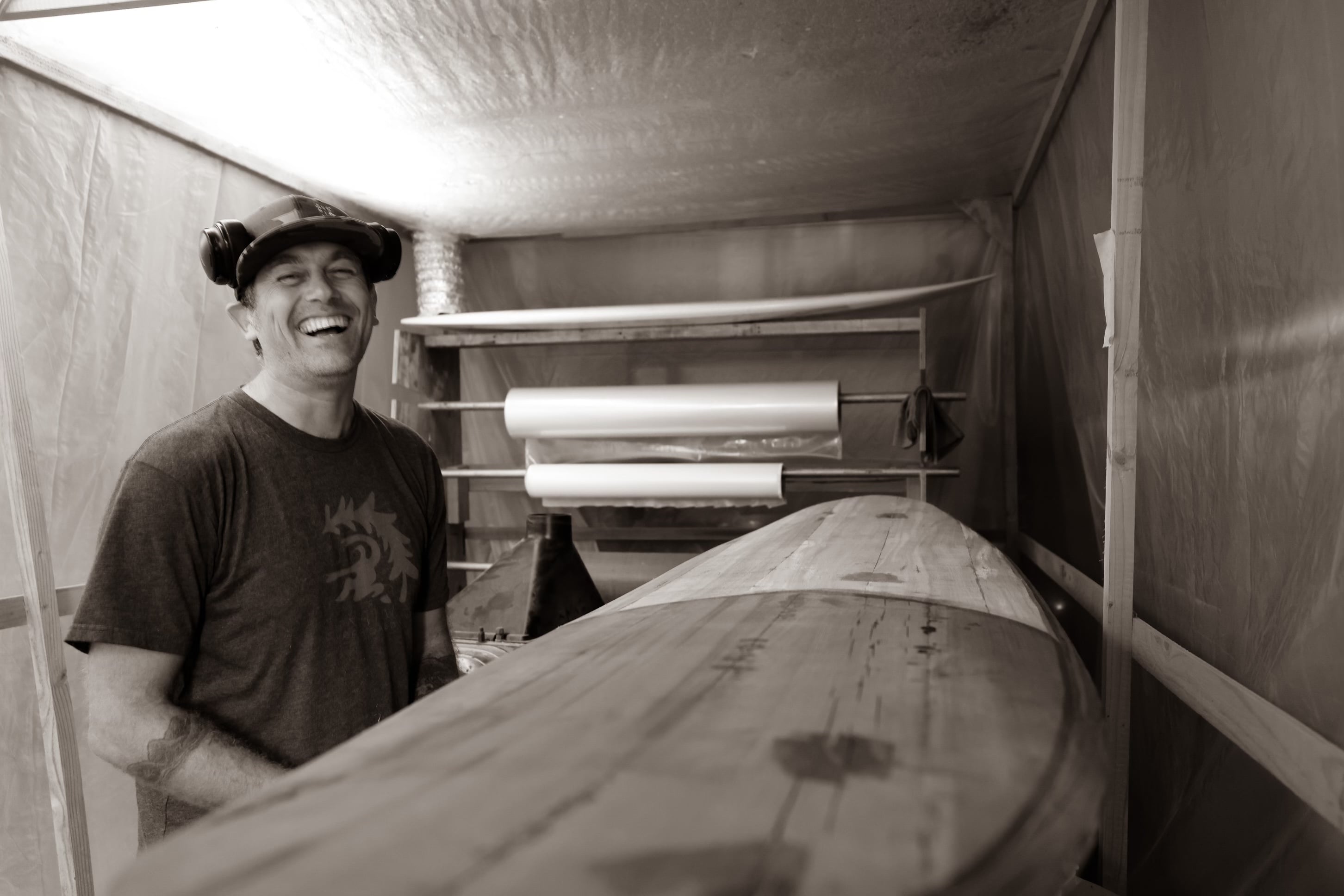 A black and white photo of Rise Up Surfboards’ Tom Loomis in the shaping room.